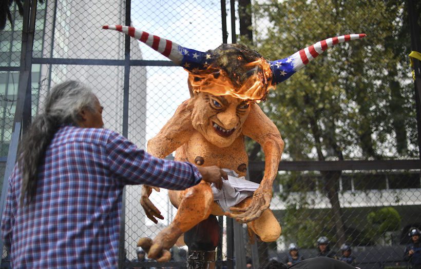 Mexican peasants burn an "Alebrije", traditional Mexican figure, with the face of US President Donald Trump in front of the US embassy building during a protest against the wall between Mexico and the US borders, in Mexico City on January 31, 2017. Mexico's unpopular President Enrique Pena Nieto got a small boost in an opinion poll published Tuesday following his confrontation with Donald Trump over the US leader's border wall plan. / AFP PHOTO / YURI CORTEZ