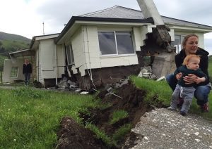 This photo taken and received on November 14, 2016 shows a woman and child in front of a house damaged by an earthquake as it sits on the fault line at Bluff Station near Kaikoura on the South Island's east coast. A powerful 7.8-magnitude earthquake killed two people and caused massive infrastructure damage in New Zealand, but officials said they were optimistic the death toll would not rise further. The jolt, one of the most powerful ever recorded in the quake-prone South Pacific nation, hit just after midnight near the South Island coastal town of Kaikoura. / AFP PHOTO / RADIO NEW ZEALAND / ALEX PERROTTET / - New Zealand OUT / RESTRICTED TO EDITORIAL USE MANDATORY CREDIT "AFP PHOTO / RADIO NEW ZEALAND / ALEX PERROTTET" NO MARKETING NO ADVERTISING CAMPAIGNS - DISTRIBUTED AS A SERVICE TO CLIENTS