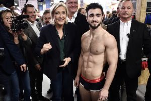 President of the French far-right party and presidential candidate for the 2017 French presidential elections Marine Le Pen (C) stands next to a man in underwear during a visit to the stand of underwear manufacturer Garcon Francais at the 5th edition of the "Made In France" fair, on November 18, 2016 in Paris. / AFP PHOTO / PHILIPPE LOPEZ