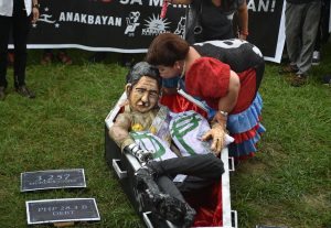 Activist Mae Paner aka Juana Change, dressed as former first lady Imelda Marcos, kisses a life-size paper mache depicting the the late dictator Ferdinand Marcos during a protest near Malacanang palace against the burial of Marcos at the heroes' cemetery in Manila on November 25, 2016 Braving a storm and rains, some 3,000 protesters marched on a central Manila park to demand that President Rodrigo Duterte and the Supreme Court remove the body from the cemetery, a week after the long-dead former president's internment. / AFP PHOTO / TED ALJIBE