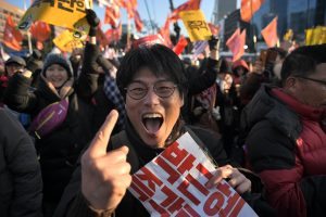 A protester reacts after the South Korean parliament's successful impeachment of President Park Geun-Hye as crowds gather outside the National Assembly in Seoul on December 9, 2016. South Korean lawmakers began voting on an impeachment motion to strip President Park Geun-Hye of her sweeping executive powers over a corruption scandal that has paralysed her administration and triggered massive street protests / AFP PHOTO / Ed JONES