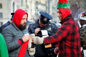 A police officer writes a ticket citing revellers for drinking alcohol in public during the annual Santacon on December 10, 2016, in New York The annual event sees people in Santa Claus suits visiting their favorite bars. / AFP PHOTO / KENA BETANCUR
