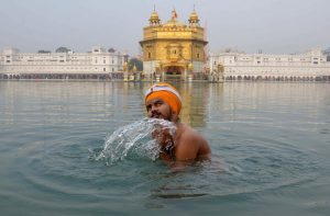 An Indian Sikh devotee takes a dip in the holy sarovar (water tank) at The Sikh Shrine Golden Temple in Amritsar on January 5, 2017, during a 'Jalau', a splendour show of Sikhism's symbolic items. The 'Jalau' took place on the occasion of the 350th birth anniversary of the tenth Sikh Guru Gobind Singh. / AFP PHOTO / NARINDER NANU