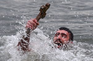 Greek Orthodox swimmer Nicolaos Solis holds a wooden cross retrieved from the Bosphorus river's Golden Horn, as part of celebrations of the Epiphany day at the Church of Fener Orthodox Patriarchate in Istanbul, on January 6, 2017. Similar celebrations for the Epiphany Day are held across the country and region on river banks, seafronts and lakes. / AFP PHOTO / OZAN KOSE