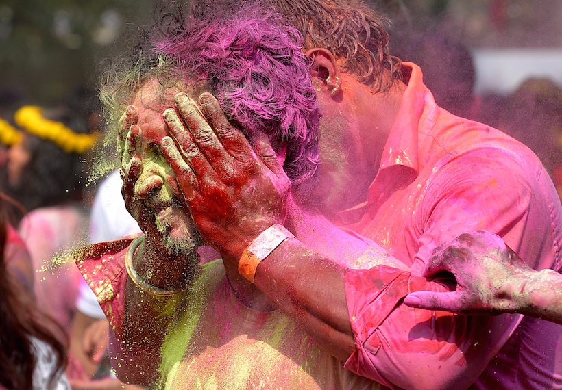 An Indian reveller reacts as he is smeared with coloured powder by a friend during Holi celebrations in Bangalore on March 13, 2017. Holi, the festival of colours, is a riotous celebration of the coming of spring and falls on the day after full moon annually in March. / AFP PHOTO / MANJUNATH KIRAN