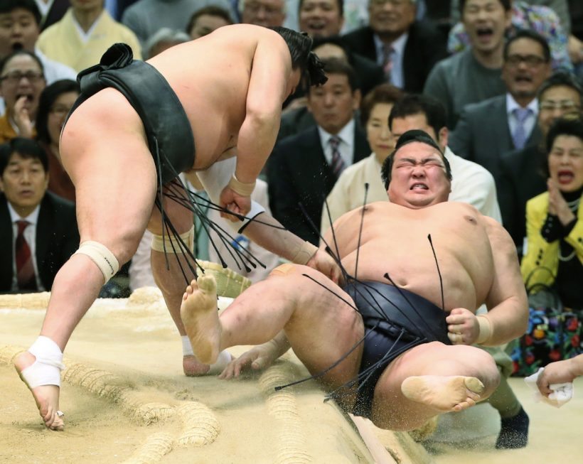 Japanese "yokozuna" or sumo grand champion Kisenosato (R) is thrown out of the ring by Mongolian yokozuna Harumafuji (L) during their bout at the Spring Grand Sumo Tournament in Osaka on March 24, 2017. / AFP PHOTO / JIJI PRESS / JIJI PRESS / Japan OUT