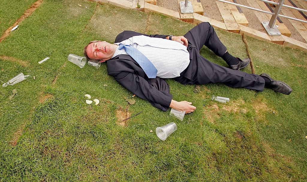 ASCOT, UNITED KINGDOM - JUNE 20: A man lies on the ground as race-goers walk past him on the first day of Royal Ascot, at the Ascot Racecourse on June 20, 2006 in Ascot, England. The event has been one of the highlights of the racing and social calendar since 1711, and the royal patronage continues today with a Royal Procession taking place in front of the grandstands daily. (Photo by Scott Barbour/Getty Images)