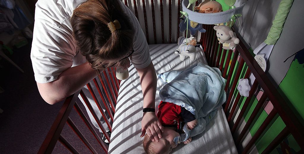 DECATUR, IL - FEBRUARY 18: Katrisa Parks puts her eight-month-old son Skyler down for a nap in the room they share at the Decatur Correctional Center February 18, 2011 in Decatur, Illinois. Skyler, who was born while Parks was serving a ten-year sentence for burglary, lives with his mother at the prison, part of the Moms with Babies program at the minimum security facility. The program allows incarcerated women to keep their newborn babies with them for up to two years while serving their sentence. The program boasts a zero percent recidivism rate compared to the statewide rate of 51.3 percent. (Photo by Scott Olson/Getty Images)