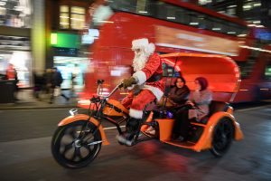 LONDON, ENGLAND - DECEMBER 20: A man dressed as Father Christmas rides a cycle taxi along Oxford Street on December 20, 2016 in London, England. With only a handful of shopping days left before Christmas, the buying public has been taking advantage of every moment to pick up their gifts. (Photo by Leon Neal/Getty Images)