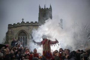 DONCASTER, ENGLAND - JANUARY 06: The Haxey Fool, Dale Smith, delivers his speech during the 'Smoking of the Fool' as he starts the Haxey Hood at Haxey Village on January 6, 2017 in Doncaster, England. The origins of the ancient game of Haxey Hood goes back hundreds of years to the 14th century. Lady de Mowbray was out riding towards Westwoodside on the hill that separates it from the village of Haxey, when her silk riding hood was blown away by the wind, farm workers in the field rushed to help and chased the hood eventually it was caught by one of the men, but being too shy to hand it back to the lady, he gave it to one of the others to hand back to her. She thanked the farm worker who had returned the hood and said that he had acted like a Lord, whereas the worker who had actually caught the hood was a Fool. The act of chivalry and the resulting chase amused her so much she donated 13 acres of land on condition that the chase for the hood would be re-enacted each year. (Photo by Christopher Furlong/Getty Images)