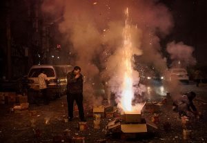 BEIJING, CHINA - JANUARY 28: A Chinese man smokes a cigarette as he and others set off firecrackers, a traditional way of warding off evil spirits, in celebration of the Chinese Lunar New Year early on January 28, 2017 in Beijing, China. China is marking the year of the Fire Rooster. (Photo by Kevin Frayer/Getty Images)